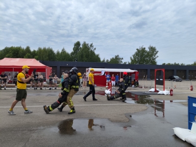 Ugunsdzēsējs glābējs pa asfaltu aiz padusēm velk smagu manekenu. Viņam nopakaļus iet tiesnesis, kas tērpies dzeltenas krāsas apģērbā