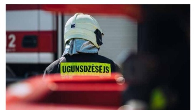 No mugurpuses redzams ugunsdzēsējs glābējs tērpies savā aizsargtērpā dodas automašīnas virzienā.