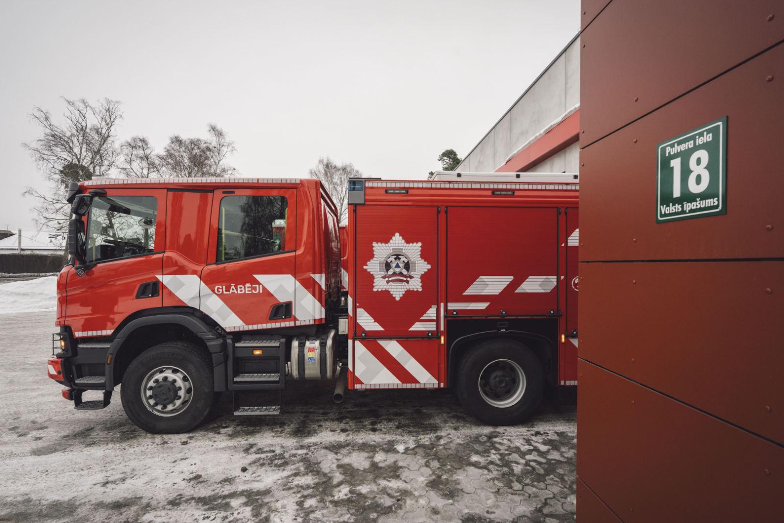 Valsts ugunsdzēsības un glābšanas dienesta specializētais transportlīdzeklis. Labajā malā Liepājas katastrofu pārvaldības centra ēkas malas, uz kuras redzama adreses plāksne - Pulvera iela 18, Liepāja