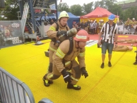 Viens ugunsdzēsējs glābējs gatavojas skriet, bet otrs ugunsdzēsējs glābējs tikmēr sakārto elpošanas aparātu, kas piestiprināts kolēģa mugurai