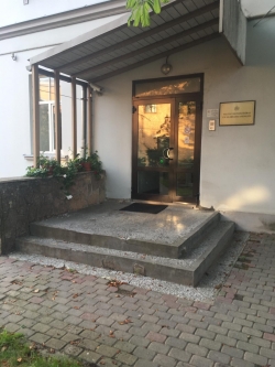 Valsts ugunsdzēsības un glābšanas dienesta ieeja - divi pakāpieni un stiklotas durvis, kas jāatver ar roktura palīdzību. Pie durvīm uz sienas ir redzama plāksne ar iestādes nosaukumu.