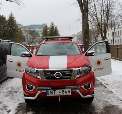 No priekšpuses redzams sarkanbaltais VUGD mikroautobuss. Atvērtas abas priekšējās durvis.