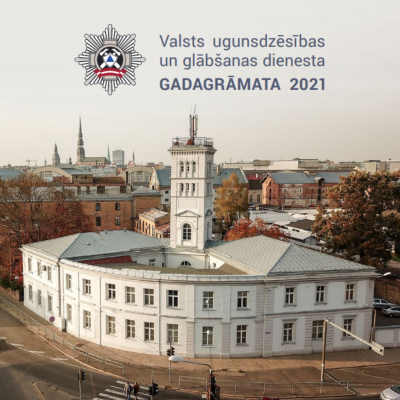 Augšpusē teksts: Valsts ugunsdzēsības un glābšanas dienesta Gadagrāmata 2021. Apakšpusē redzama baltā VUGD ēka, kas atrodas krustojumā.