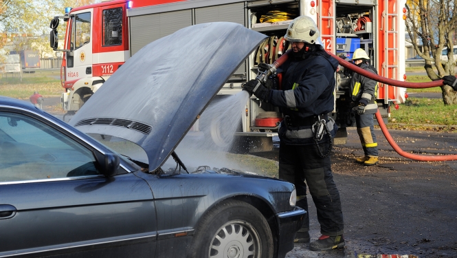 Ugunsdzēsējs glābējs dzēš degošu automašīnu