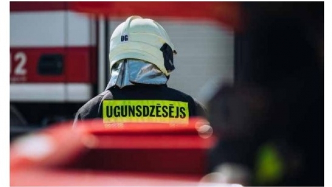 No mugurpuses redzams ugunsdzēsējs glābējs tērpies savā aizsargtērpā dodas automašīnas virzienā.