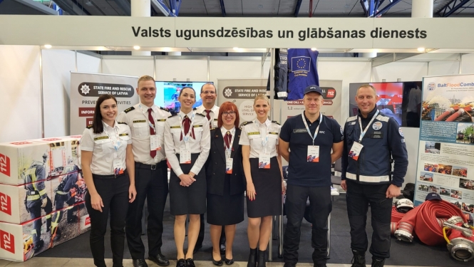 VUGD pārstāvju kopbilde. Fonā redzami novietotie izstādes stendi.