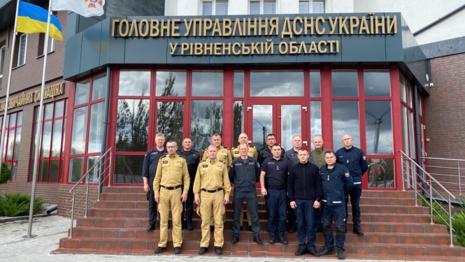 VUGD darbinieki un citu valstu pārstāvji stāv uz kāpnēm pie Ukrainas Valsts Ārkārtas situāciju dienesta ēkas