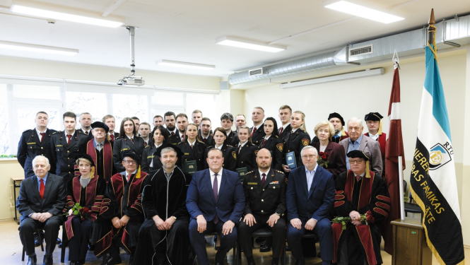 Izlaiduma dalībnieku kopbilde. Pirmajā rindā cilvēki sēž uz krēsliem, bet viņiem aiz muguras stāv citi izlaiduma dalībnieki un absolventi.