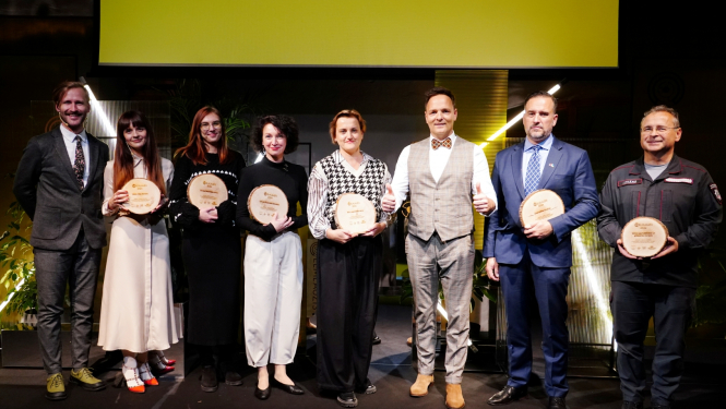 Uz skatuves viens otram blakus stāv astoņi cilvēki - četri vīrieši un četras sievietes. Seši no cilvēkiem tur rokās iegūtās Celmlaužu ripas, kas izgatavotas no koka.