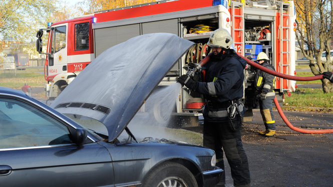 Ugunsdzēsējs glābējs dzēš degošu automašīnu