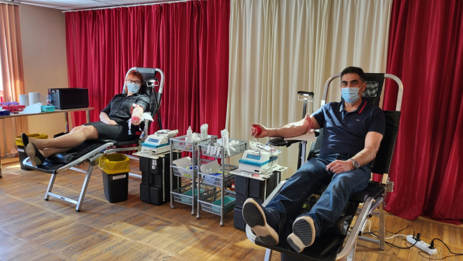 Divi cilvēki sēž katrs savā krēslā un ziedo asinis