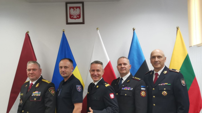 Kopbilde, kurā redzami pieci sadarbības memoranda dalībvalstu pārstāvji. Viņiem aiz muguras redzami pārstāvēto valstu karogi.