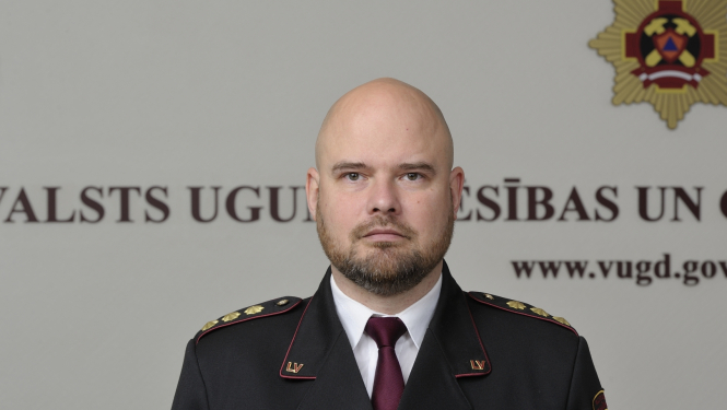 Valsts ugunsdzēsības un glābšanas dienesta priekšnieka vietnieks pulkvedis stāv un skatās fotogrāfa virzienā