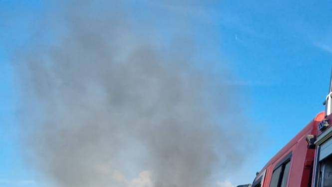 Divi ugunsdzēsēji glābēji dzēš degošu koka māju