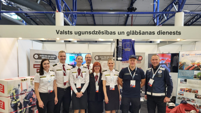 VUGD pārstāvju kopbilde. Fonā redzami novietotie izstādes stendi.