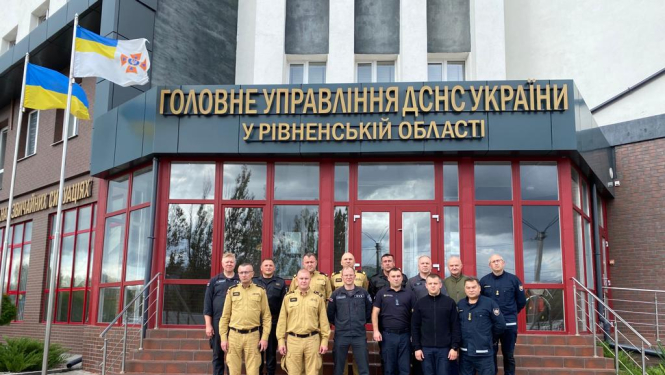 VUGD darbinieki un citu valstu pārstāvji stāv uz kāpnēm pie Ukrainas Valsts Ārkārtas situāciju dienesta ēkas