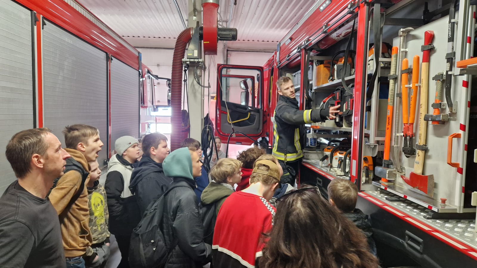 Labajā malā atrodas ugunsdzēsēju glābēju autocisterna, kam atvērts viens sāns, lai telpā esošie jaunieši varētu apskatīt autocisternā esošos instrumentus un aprīkojumu.