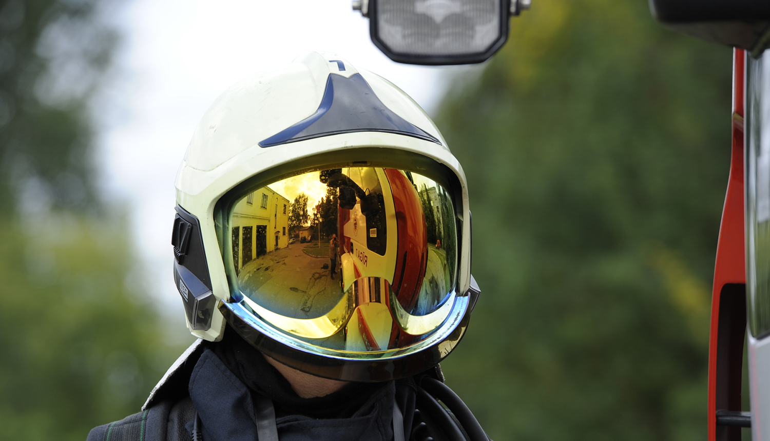 Ugunsdzēsējs glābējs, kurš sev galvā uzvilcis aizsargķiveri. Ķiveres aizsargstikls ir nolaists uz leju, tādējādi aizsedzot ugunsdzēsēja glābēja seju.