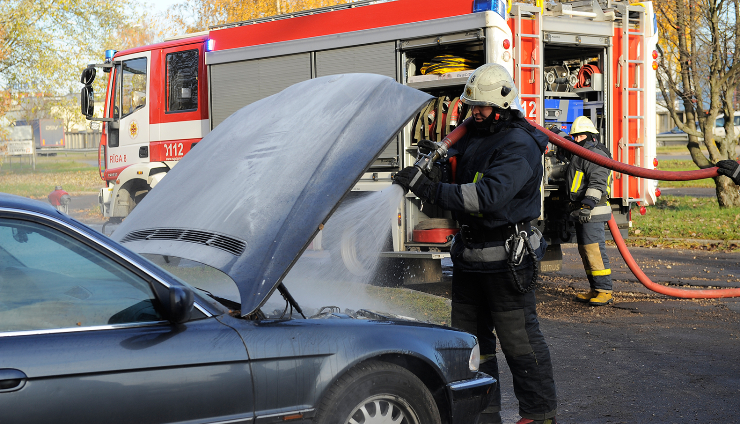 Ugunsdzēsējs glābējs dzēš degošu automašīnu