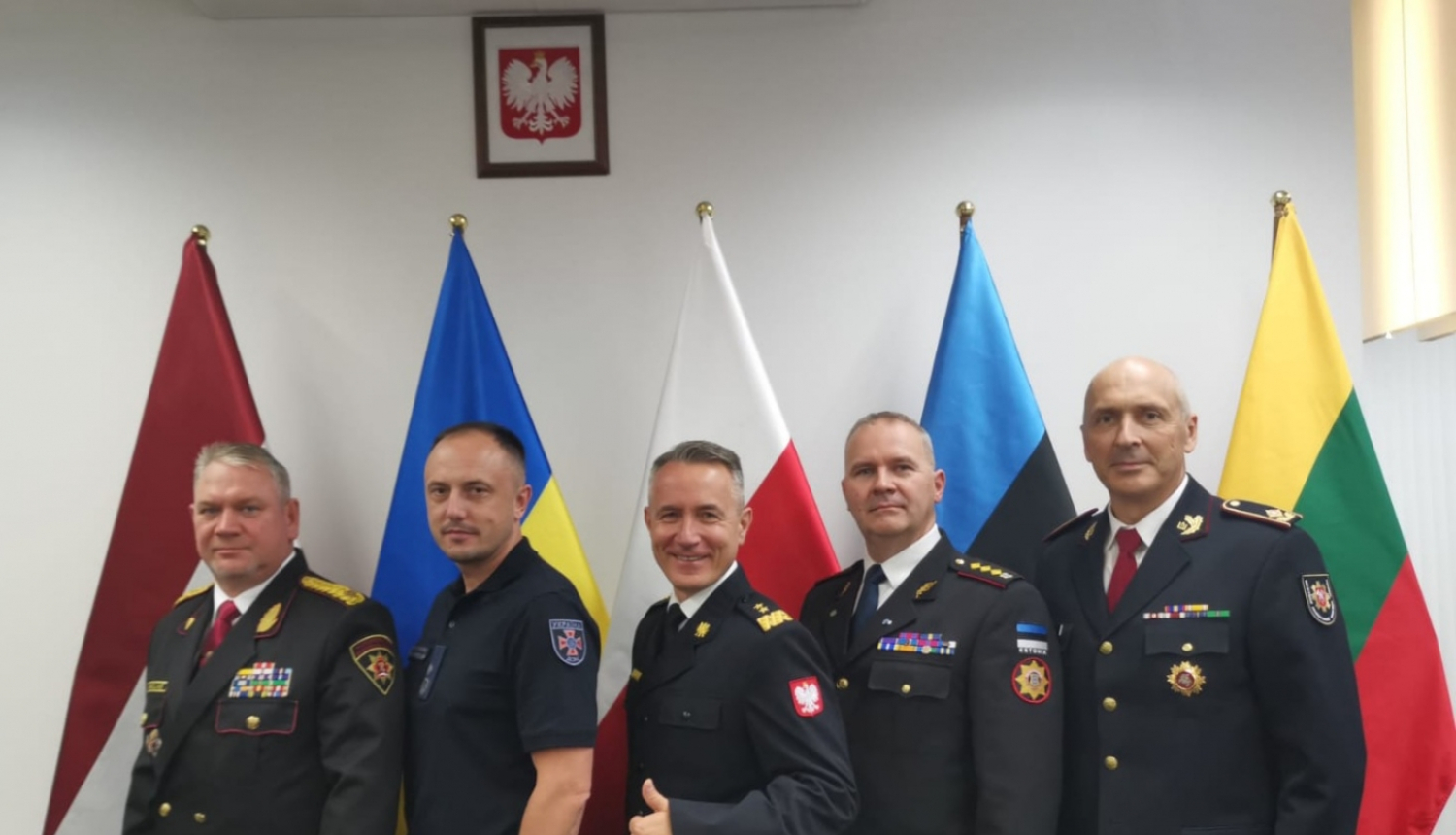 Kopbilde, kurā redzami pieci sadarbības memoranda dalībvalstu pārstāvji. Viņiem aiz muguras redzami pārstāvēto valstu karogi.