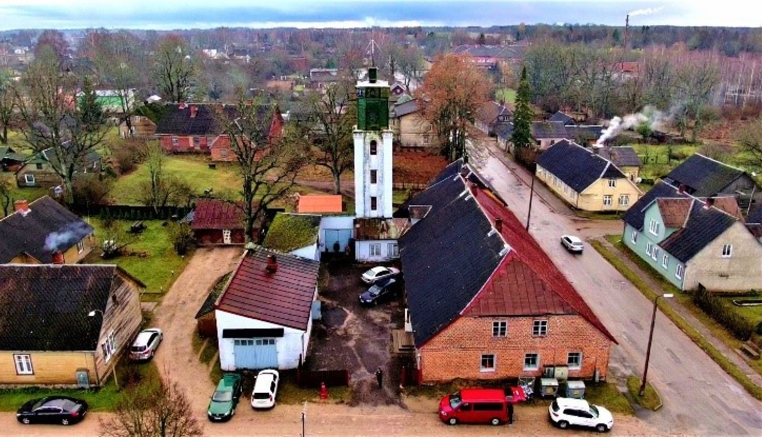 Skats no augšpuses uz dažām Rūjienas mājām. To vidū izceļas balts tornis.