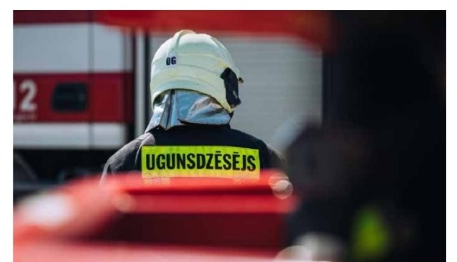 No mugurpuses redzams ugunsdzēsējs glābējs tērpies savā aizsargtērpā dodas automašīnas virzienā.