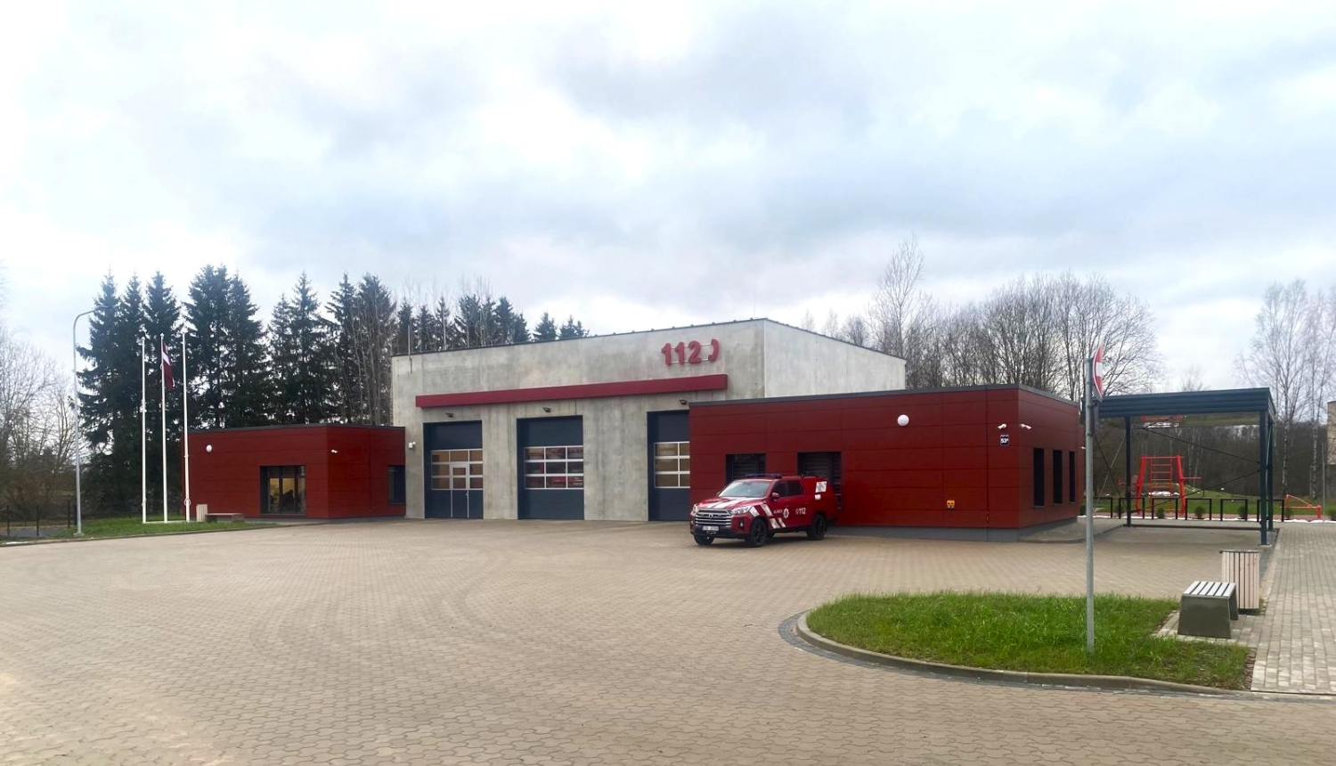 Sarkani balta krīzes pārvaldības ēka pie kuras novietota viena automašīna. Aiz tās zaļi skujkoki. 