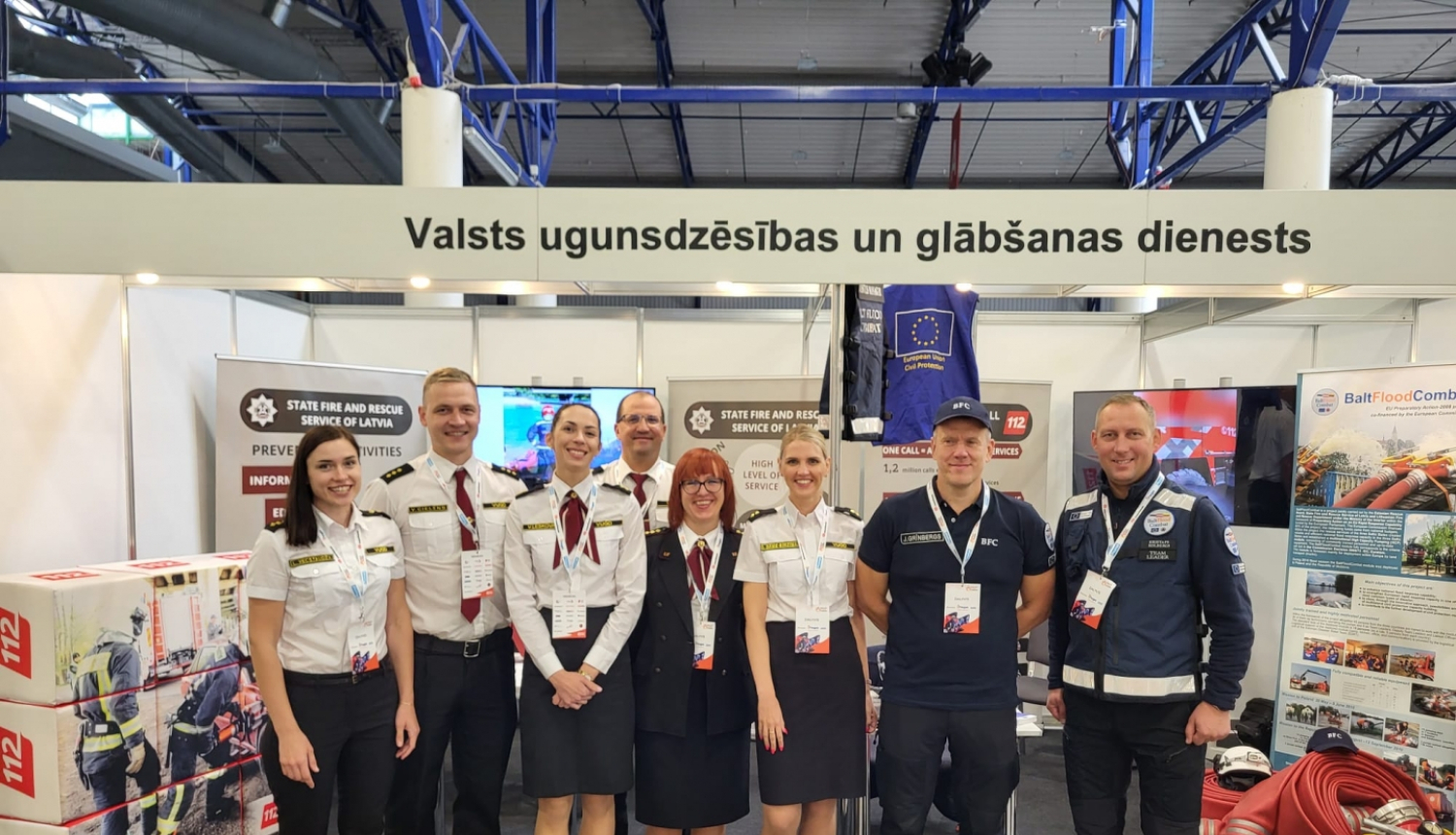 VUGD pārstāvju kopbilde. Fonā redzami novietotie izstādes stendi.