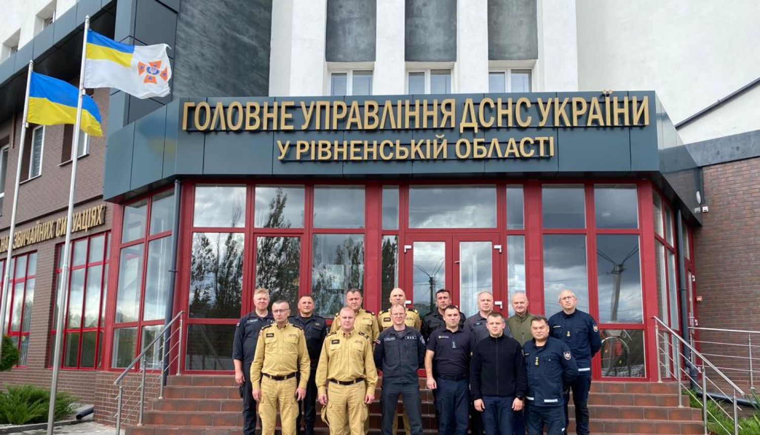 VUGD darbinieki un citu valstu pārstāvji stāv uz kāpnēm pie Ukrainas Valsts Ārkārtas situāciju dienesta ēkas