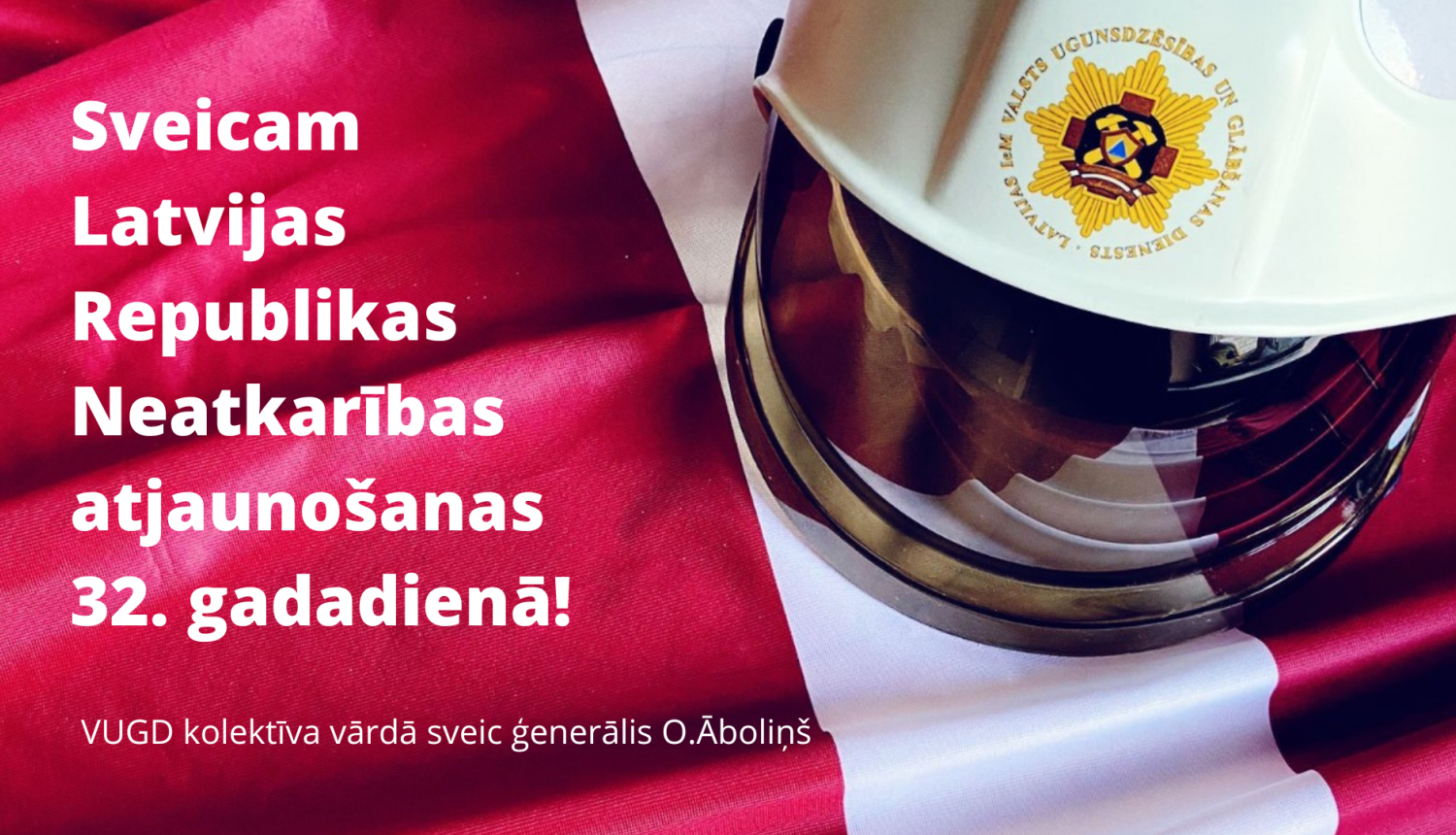Apsveikums: "Sveicam Latvijas Republikas Neatkarības atjaunošanas 32.gadadienā! VUGD kolektīva vārdā sveic ģenerālis O.Āboliņš". Fonā redzams Latvijas valsts karoga fragments un VUGD ugunsdzēsēju glābēju ķivere baltā krāsā