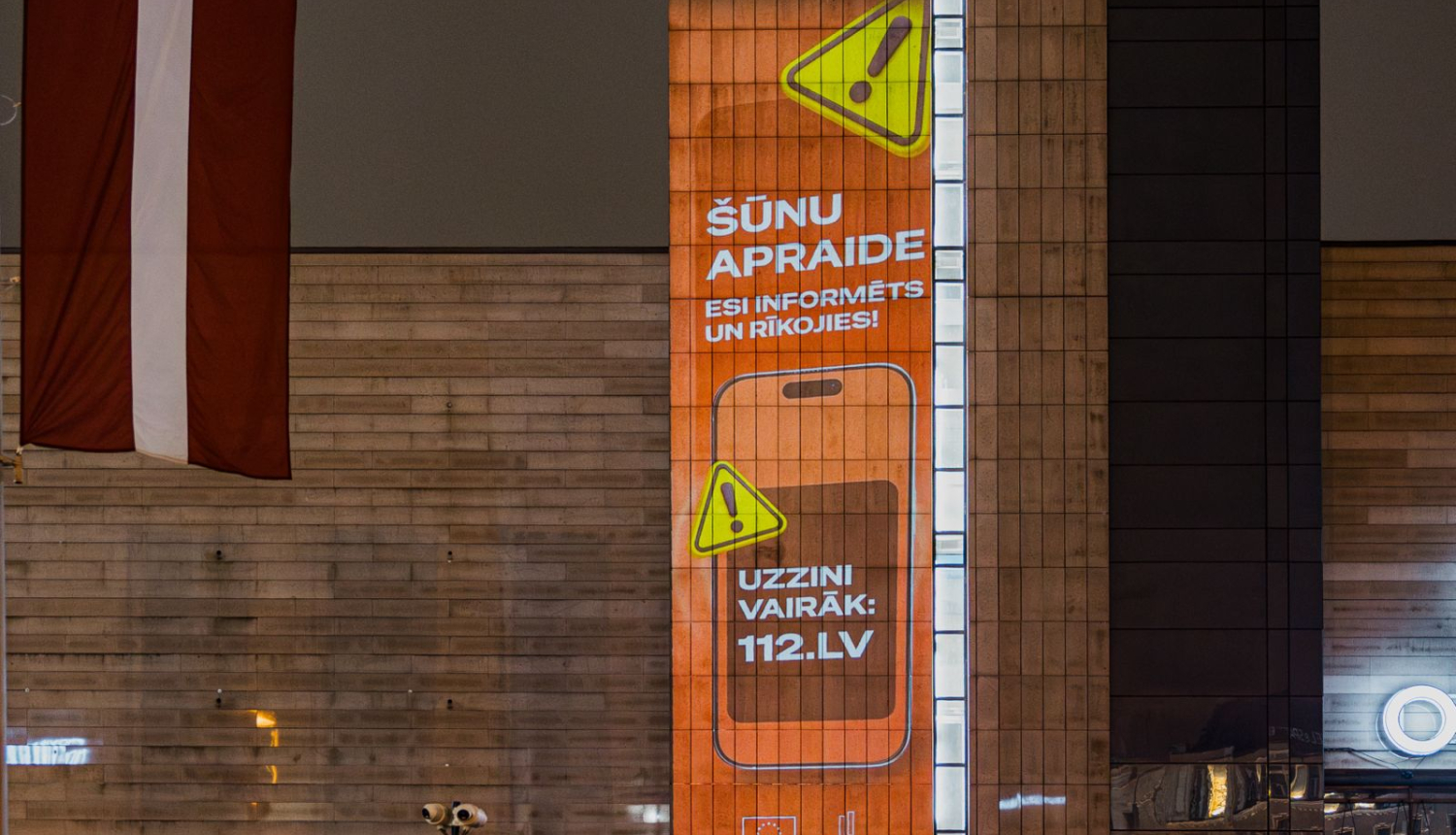 Uz spoguļotas virsmas organžas krāsas Šūnu apraides kampaņas vizuālis ar informāciju par kampaņu