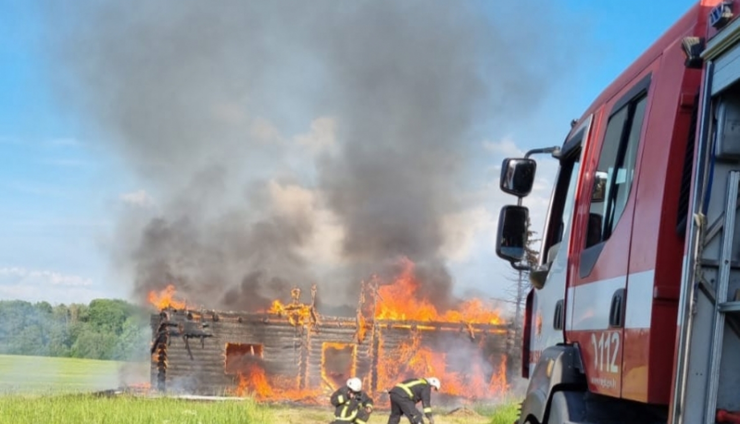 Divi ugunsdzēsēji glābēji dzēš degošu koka māju