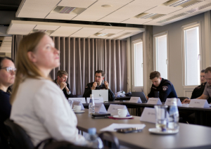 Sanāksmju zāle. Ap galdu sasēdušies projekta pārstāvji. 