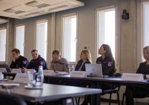 Sanāksmju zāle. Pie galda sasēdušies projekta pārstāvji. 